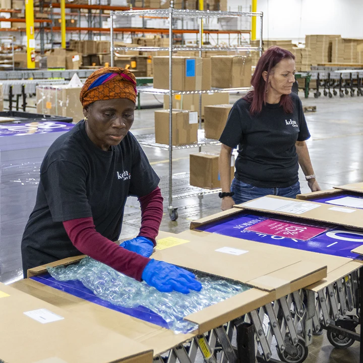 Two women packing signage kits in a warehouse