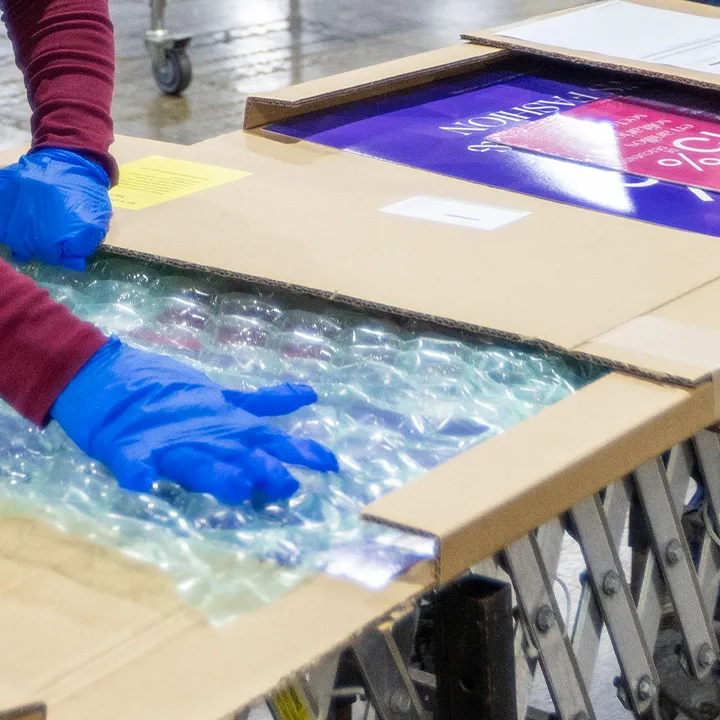 Two women packing signage kits in a warehouse